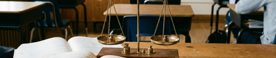 Classroom desk with mathematics book, balance scale, and graded exams